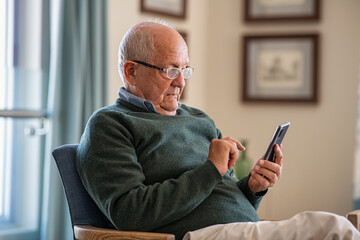 senior man using smartphone at home