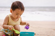 © TimmyTimTim - Asian boy child playing sand with his bucket on the beach in front of sea.