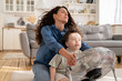 Relaxed mom and little kid sit with closed eyes at fan in living room refreshing from summer heat outdoors enjoy fresh cold air blow. Mommy and preschool son relaxing at home in summertime together