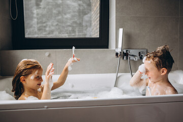 Wall Mural - Sister and brother washing in bathroom full of bubbles