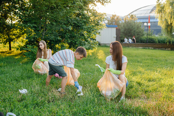 A group of girls with children at sunset are engaged in garbage collection in the park. Environmental care, recycling.