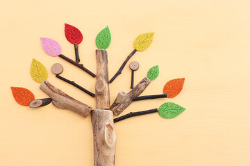 Image of wooden growing tree on pastel yellow background