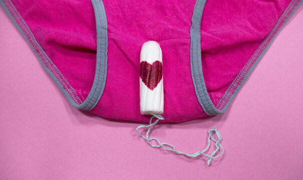 Cotton tampon on woman's underwear with red heart as a symbol of blood.