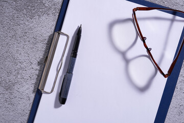 Canvas Print - blank clipboard with pen and eyewear  on cement background