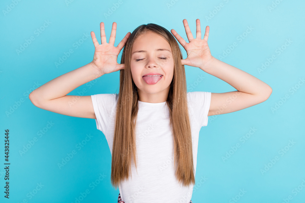 Photo of sweet brown hair little girl hands head tongue out wear white t-shirt isolated on blue color background - obrazy, fototapety, plakaty 