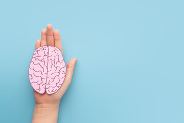 Wall Mural - Woman hands holding human brain shape made from paper on light blue background. Awareness of Alzheimer, Parkinson's disease, dementia, stroke, seizure or mental health. Neurology and Psychology care.