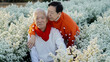© glowonconcept - Asian senior eldery couple hugging sweater celecrate Christmas and New Year holiday morning in beautiful flowers garden