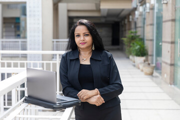 An Indian woman works on her laptop in an urban corporate setting,