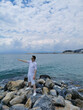 © Irina Anashkevich - Guy traveler stands on the rocks against the background of the Aegean Sea and blue sky with clouds. Kusadasi, Turkey.