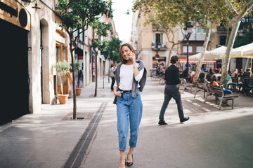 Cheerful woman talking on smartphone on street