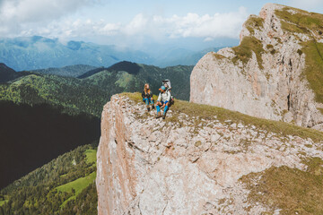 Family hiking sitting on mountain cliff travel with baby adventure vacations outdoor healthy lifestyle eco tourism wanderlust concept