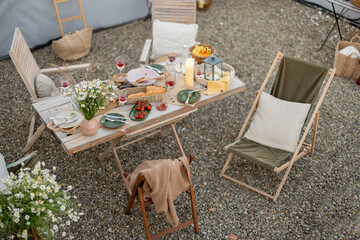 Wall Mural - Beautifully served wooden table in natural boho style outdoors. Dining table decorated with field flowers, dishes and fresh food