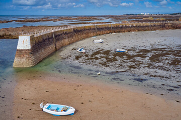 Wall Mural - Image of La Rocque Harbour at half tide with blue sky and beached boats and harbour pier, Jerey, Channel Islands, St Clement.