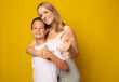 © Danko - Joyful family mother and her son in casual clothes are posing in studio with yellow background. Family portrait