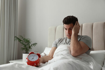 Canvas Print - Emotional man with alarm clock in bed. Being late because of oversleeping