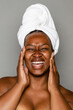 © McKinsey Jordan/Stocksy - Laughing Woman Applying Skincare Products To Her Face