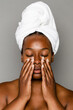 © McKinsey Jordan/Stocksy - Woman Wearing Towel Applying Product To Her Face
