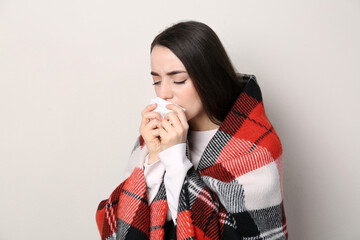 Canvas Print - Young woman with blanket suffering from runny nose on beige background