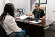 © Ezequiel Giménez/Stocksy - Smiling dentist sitting in the surgery with his patient.