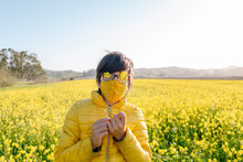Teenager In Mask Playing With Flowers In Field