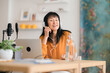 © Studio Marmellata/Stocksy - Cheerful Asian woman recording podcast in studio