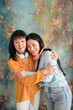 © Studio Marmellata/Stocksy - Happy Asian women hugging against colorful wall