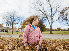 Boy Playing In Leaves In A Neighborhood Yard
