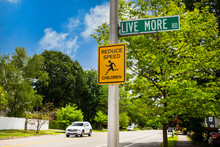 Street signs Reduce speed on a pole with a road name Live more. 
The concept of safety children on the street. 