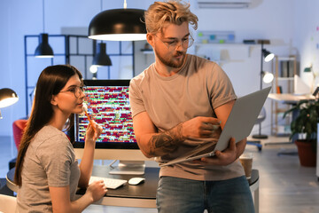 Canvas Print - Young programmers working with laptop in office at night