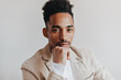 © Look! - Brunette guy in shirt looks at camera thoughtfully against isolated background. Cool brown-eyed man in beige suit posing on white backdrop