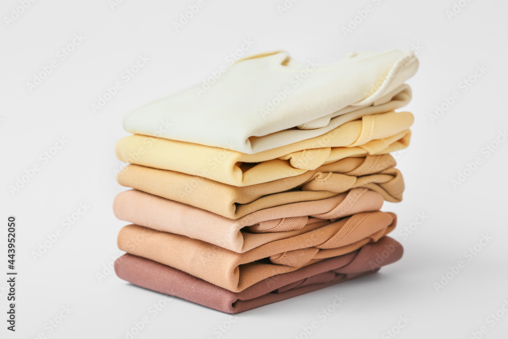 Stack of baby clothes on light background