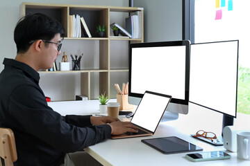 Wall Mural - Side view Asian man programer working in modern workplace.