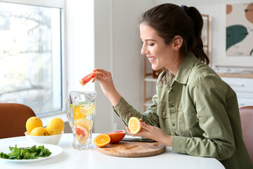 Young woman making fresh lemonade at home