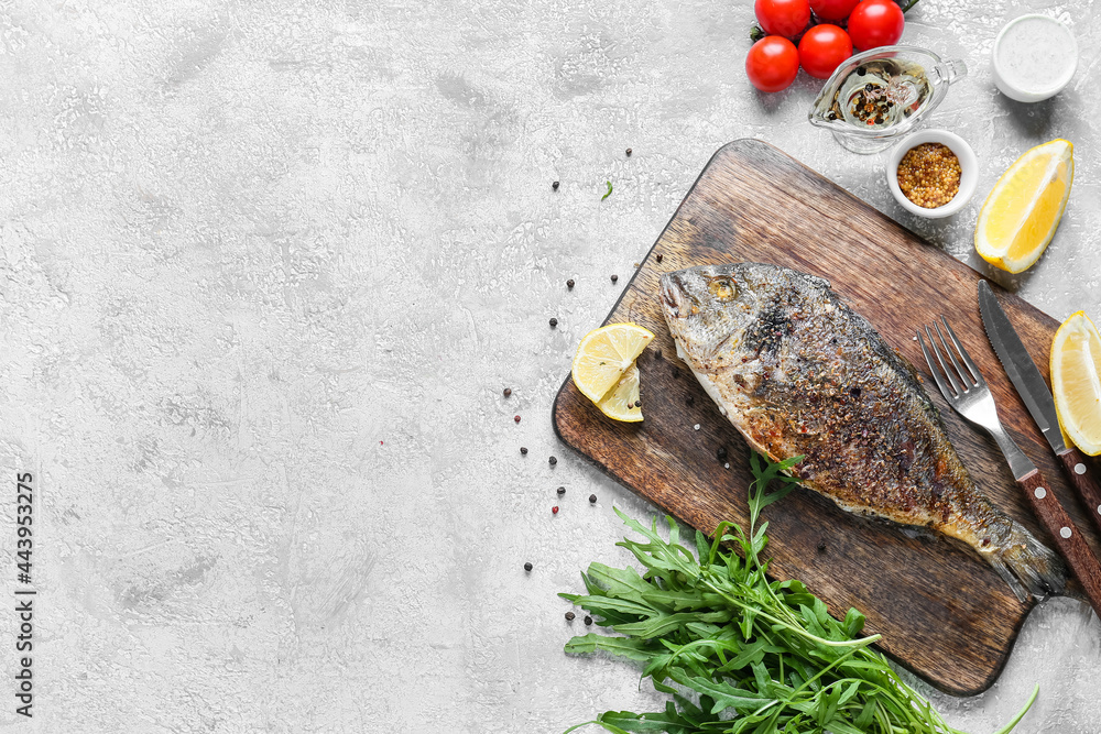 Wooden board with fried dorado on light background