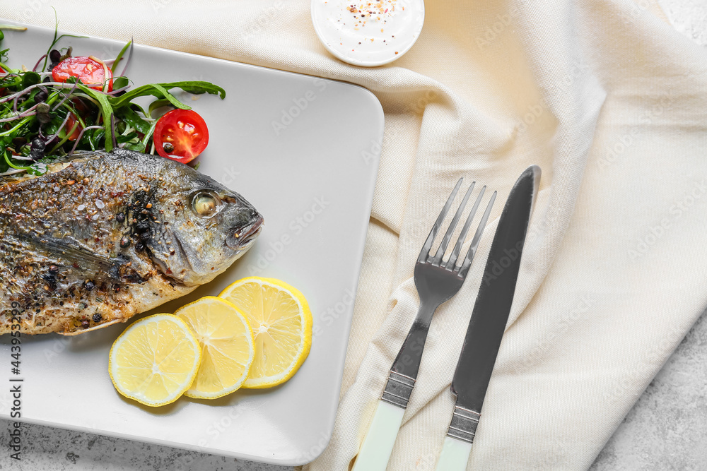 Plate with fried dorado and salad on light background