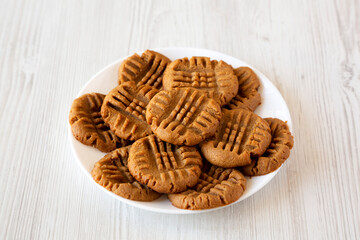 Wall Mural - Homemade Peanut Butter Cookies on a plate on a white wooden surface, side view.