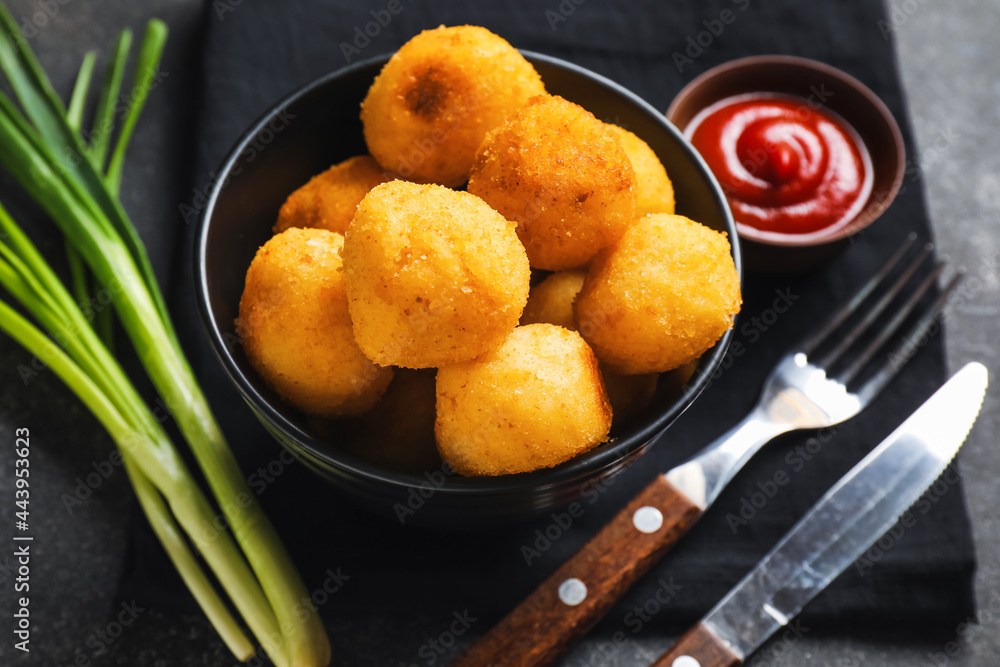 Bowl with fried potato balls and tomato sauce on napkin