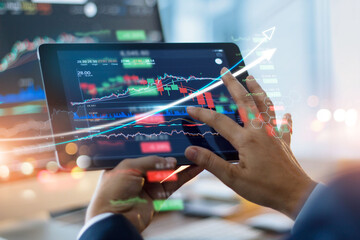 Businessman using tablet and showing a growing virtual hologram of statistics, graph and chart with arrow up on dark background. Stock market. Business growth, planing and strategy concept.