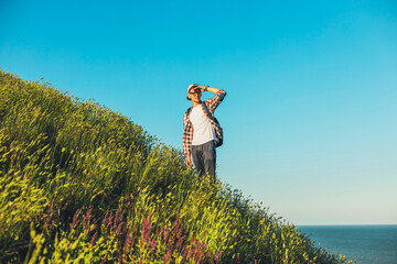 Wall Mural - Smiling young man with a backpack stands on the trail looking at the panorama while walking alone, Tourist with a backpack looking into the mountains