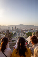 A Group Of 3 Girls Tourist Enjoying The Sunset On The Top Of A Mountain In Barcelona.