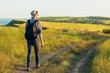 © Shopping King Louie - Smiling young man wearing glasses and cap traveling with backpack in summer, hiker hiking and observing picturesque landscape