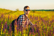 © Shopping King Louie - Young man in sunglasses sitting in a field with wildflowers, man in the countryside during sunset, enjoying nature