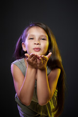 child girl sends a kiss on dark background