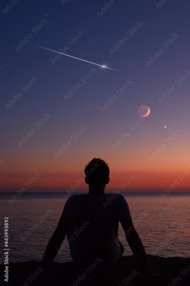 Silhouette of a man looking at the Moon and stars over sea ocean ...