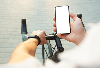 the cyclist is holding the mobile phone with blank white screen in one hand and bicycle in another o