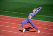 © be free - full of energy. athletic lady warming up on stadium running track. female athlete do sport workout