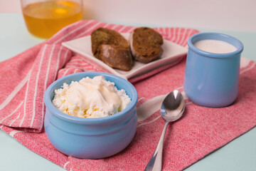 Cottage cheese in a blue bowl with sour cream and honey. Toasted bread in a plate. Morning breakfast.