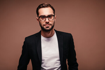 Wall Mural - Man in suit and glasses looks into camera on brown background