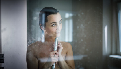 Wall Mural - Woman taking a long hot shower washing her hair in a modern design bathroom