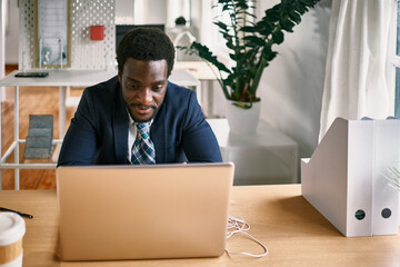 Young business african man working on laptop computer inside modern office - Focus on face